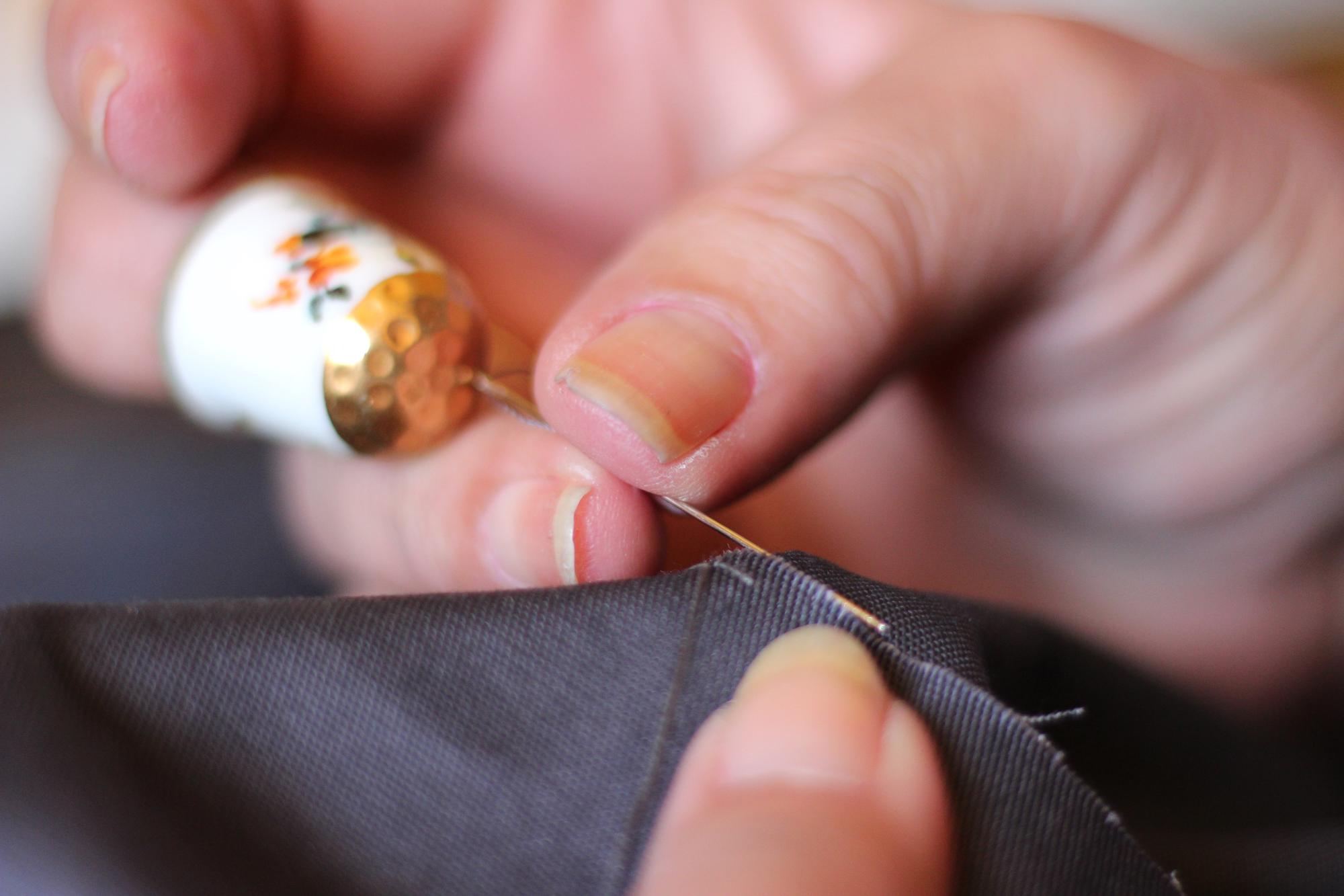 Hands embroidering with gold thread